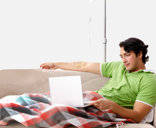An iMCD patient sitting on a couch receives their Sylvant infusion at home